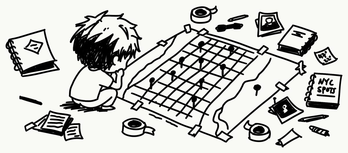 The same person crouched over a large taped-down city map covered in pins, surrounded by notebooks, tape, and a pad labelled NYC spots.
